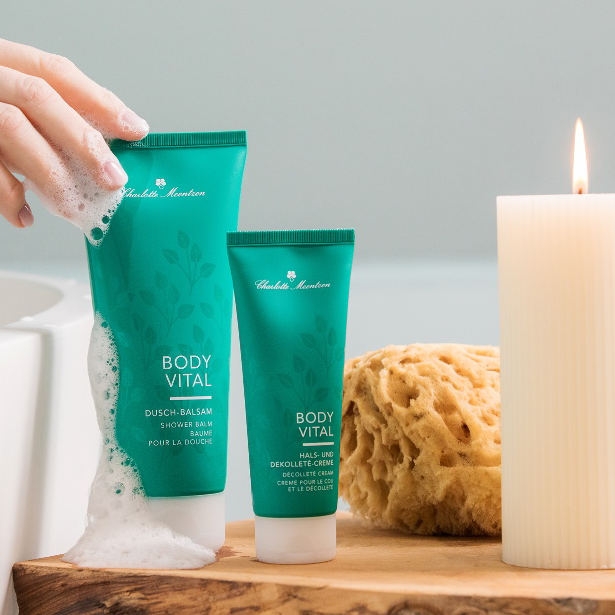 Zwei Body Vital Produkte neben Badewanne und Kerze mit Schaumhand